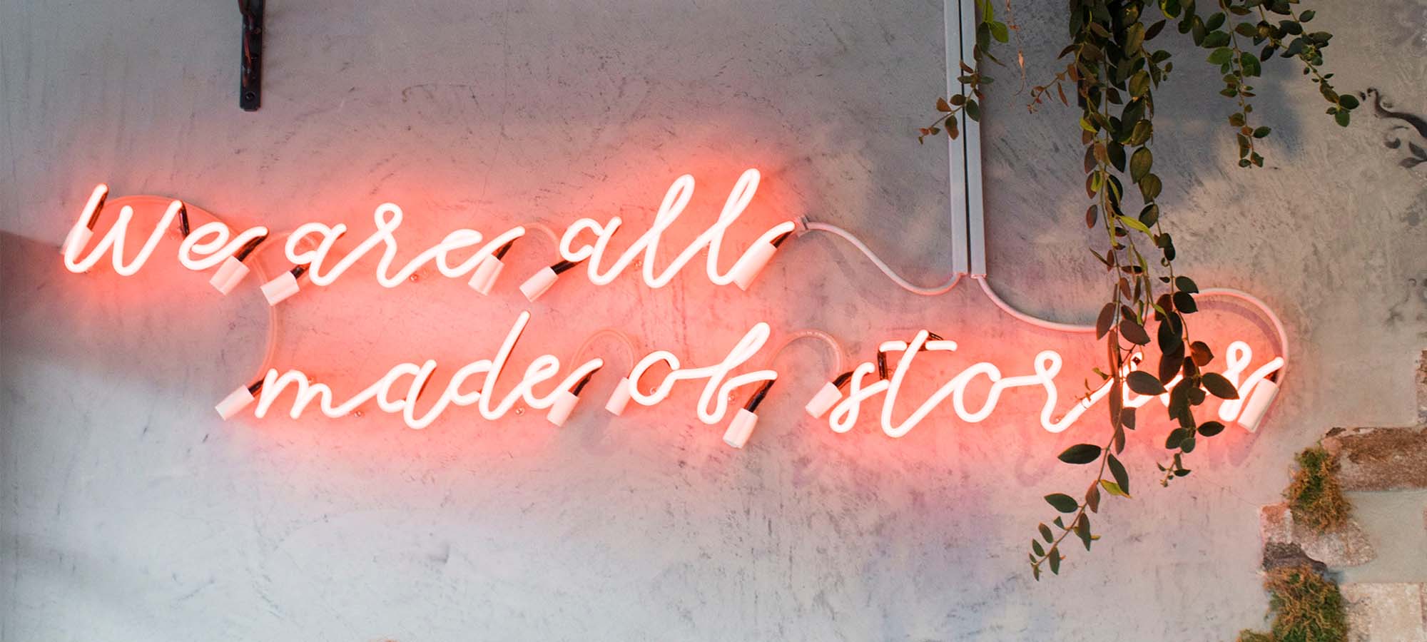 Neon sign at Red Market Miami reading “We are all made of stories”