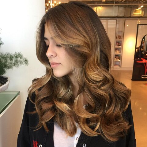 Long brown balayage waves beside the mirror wall at Red Market Miami, Bal Harbour Shops