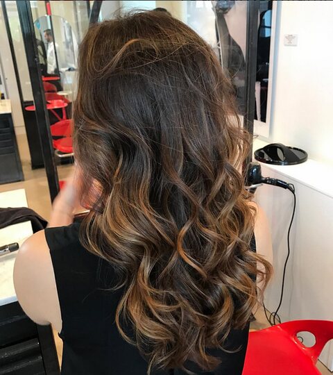 A client in the mirror beside a red styling chair at Red Market Miami