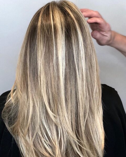 A stylist lifting newly highlighted blonde hair at Red Market Miami